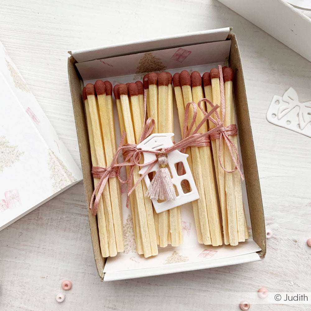 Streichholzschachtel mit rosa Schnur und einem kleinen weißen Hausanhänger, hergestellt mit Alexandra Renke Motivstanze Mini-Stadthäuser und Designpapieren, ausgestellt auf einer hellen Fläche.