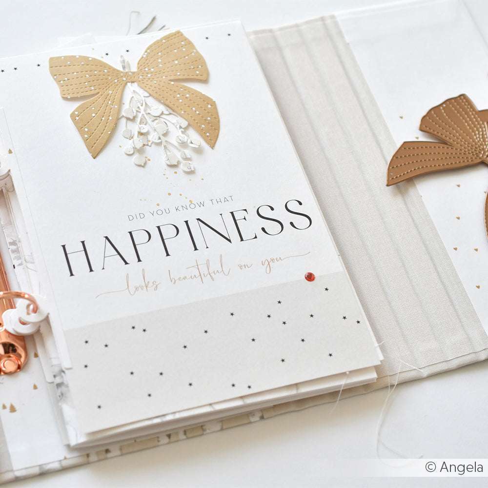 Eine dekorative Karte mit goldener Schleife, gestaltet mit Alexandra Renke Motivstanze Tütengriff Schleife, mit dem Spruch "Das Glück steht dir gut" auf hochwertigen Alexandra Renke Designpapieren vor weißem Hintergrund.