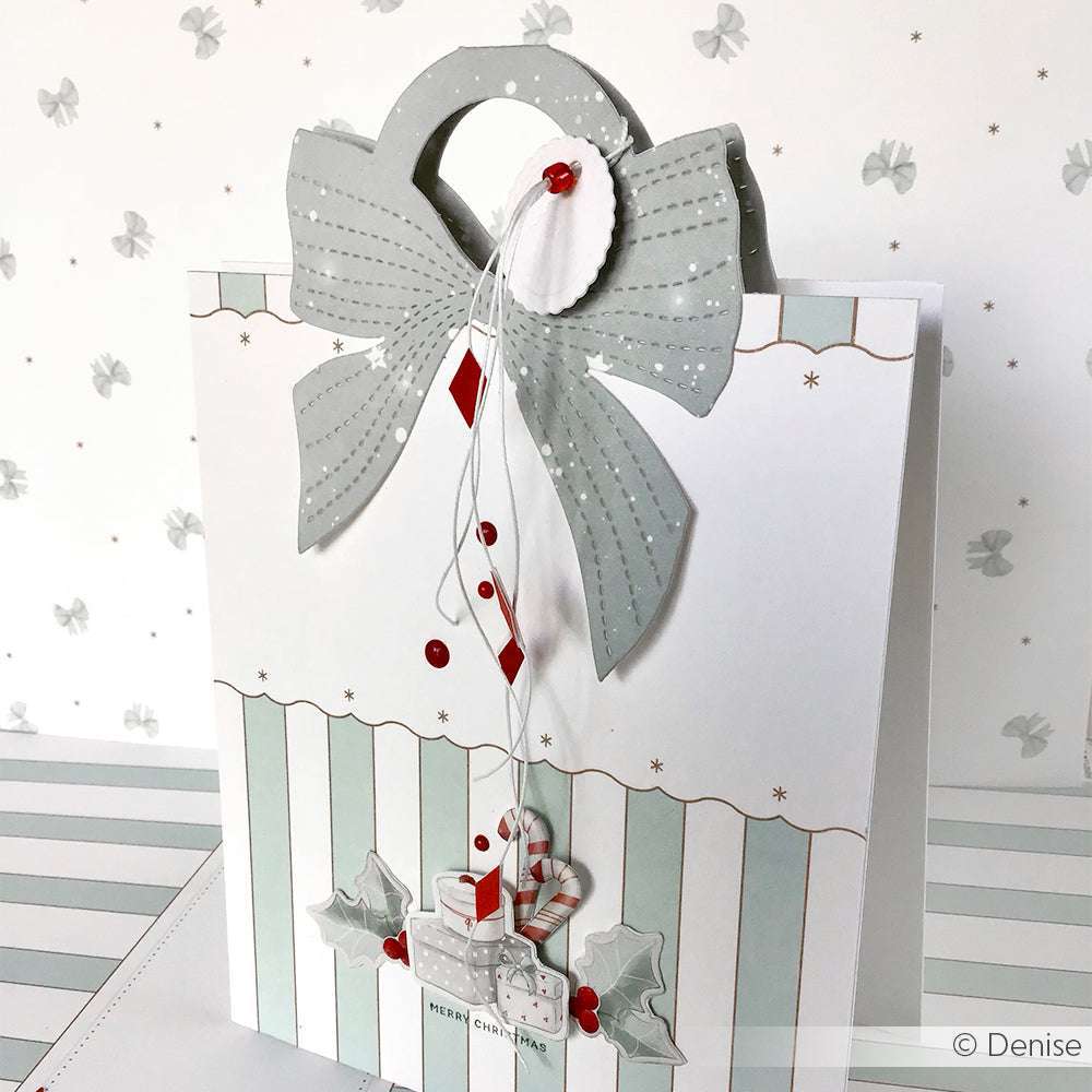 Elegante weiß-silberne Alexandra Renke Geschenktasche mit großer Schleife, Ornamenten und Weihnachtsgeschenken - ideal zum Ausstellen von Stanzen für Designpapier oder zum Kombinieren mit Ihrer Lieblings-Motivstanze Tütengriff Schleife.