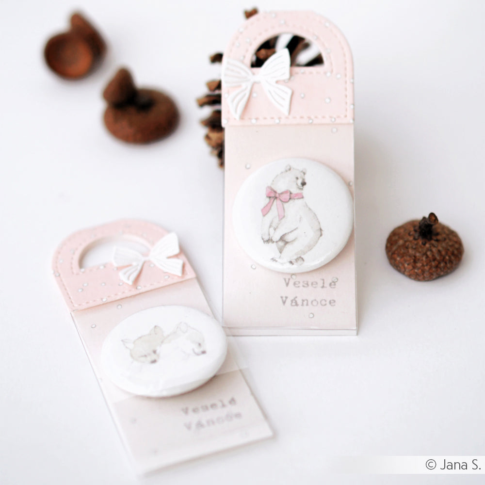 Zwei pastellfarbene Geschenkanhänger von Alexandra Renke mit niedlichen Tierillustrationen und Schleifen, umgeben von kleinen braunen Eicheldekorationen - fachmännisch hergestellt mit zarten Motivstanze-Stanzen für präzise Details.