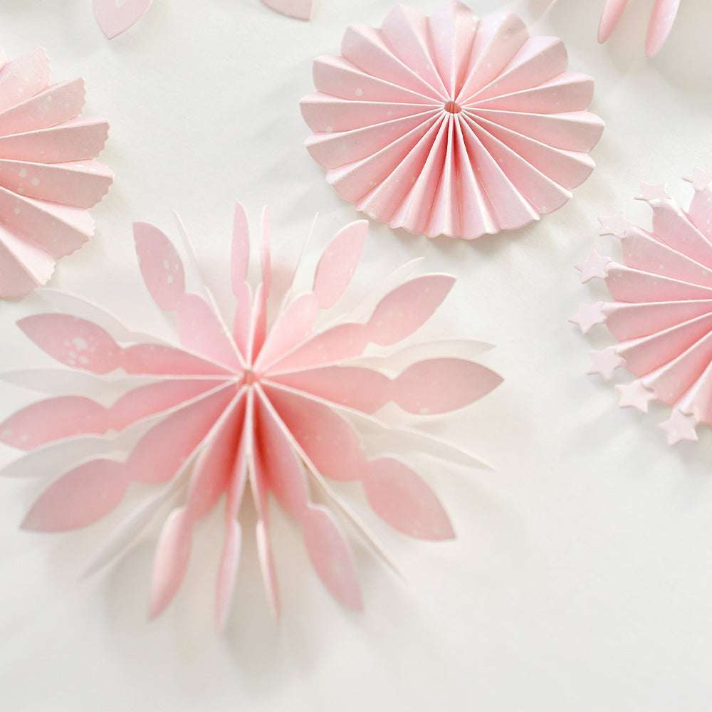 Die rosafarbenen Papierrosetten aus Alexandra Renke Designpapieren mit verschiedenen Blüten- und Sternformen sind wunderschön auf weißem Hintergrund angeordnet.
