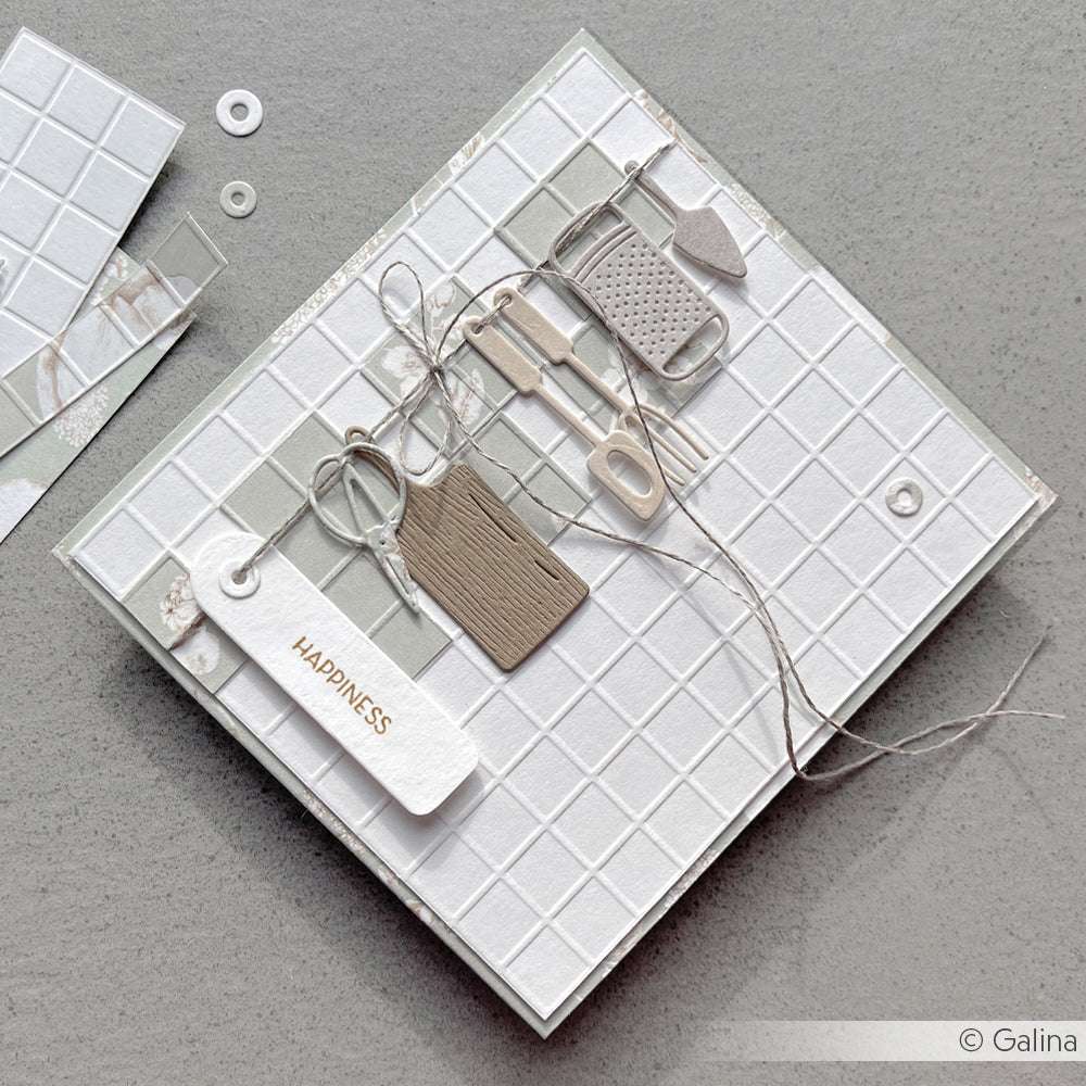 Eine handgefertigte Karte mit ausgeschnittenen Küchenutensilien aus dem Alexandra Renke Motivstanze Küchenutensilien-Set, mit Schnur und einem Anhänger mit der Aufschrift "HAPPINESS", auf einem gekachelten Hintergrund.