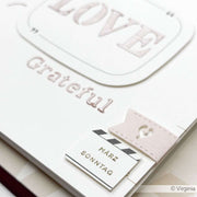 Nahaufnahme einer Karte von Alexandra Renke, gestaltet mit Designpapieren, mit den geprägten Worten "Love" und "Grateful" und einer Lasche mit der Aufschrift "März Sonntag".