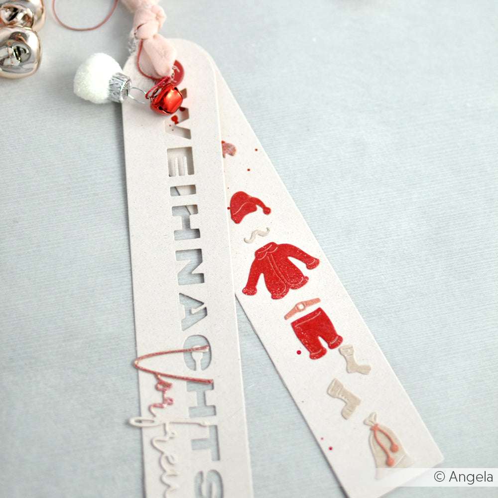 Zwei festliche Lesezeichen aus Papier mit roten Winterkleidungsmotiven und deutschem Text, verziert mit Glöckchen und Schleife - hergestellt mit Alexandra Renkes Motivstanze Großes Etikett L und hochwertigen Designpapieren für einen charmanten Weihnachtslook.