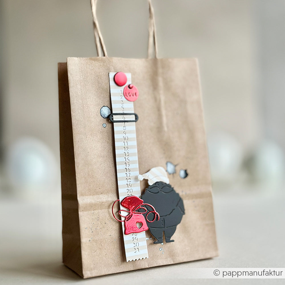 Braune Geschenktüte von Alexandra Renke mit Weihnachtsmannfigur, Lineal, roten festlichen Details und dekorativen Akzenten aus Motivstanze Kalenderstreifen Designpapiere.