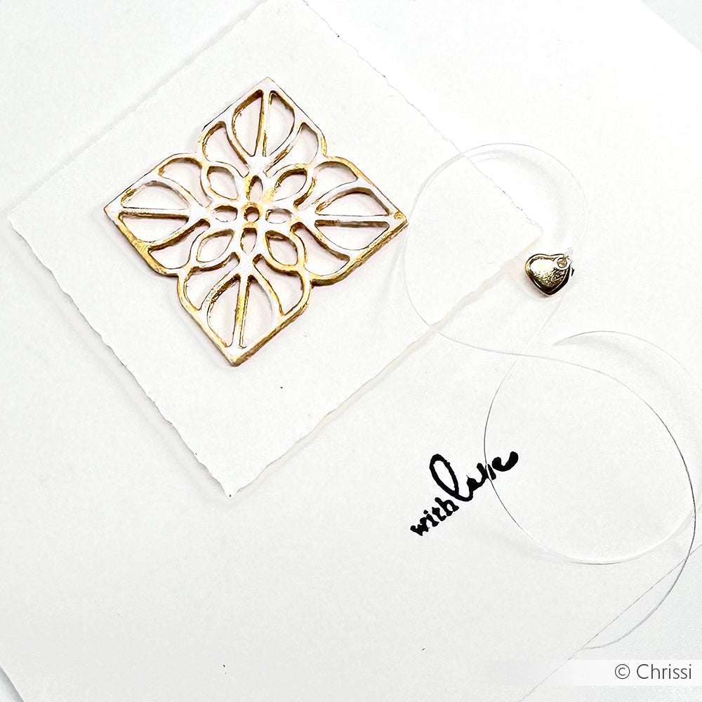 Eine goldene Blumenkarte mit "With Love"-Text und Herzanhänger auf weißem Grund, hergestellt mit Alexandra Renke Motivstanze Ornament mit Kontur und eleganten Designpapieren für eine einzigartige, herzliche Note.