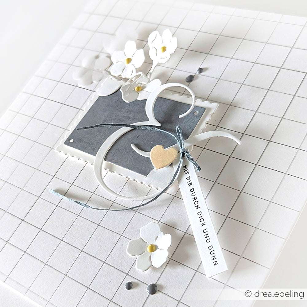 Handgefertigte Karte mit weißen Blumen, einem grauen Quadrat, einem Band, einem Herz und einem Gitterhintergrund, hergestellt mit Alexandra Renke Designpapieren für eine einzigartige Note.