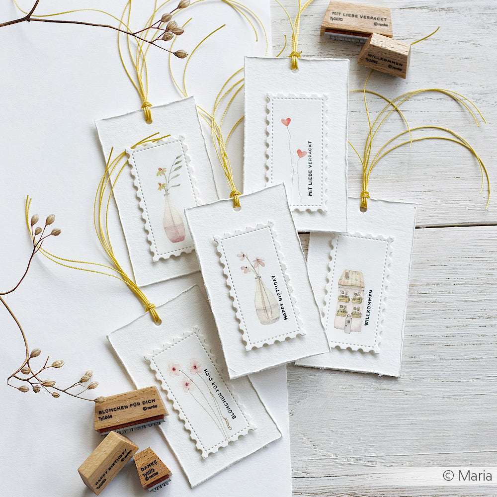Sechs handgefertigte Geschenkanhänger mit zarten floralen Motiven und gelber Kordel, die mit kleinen Gummistempeln versehen sind, werden mit Alexandra Renke Designpapieren und der Motivstanze Großes Briefmarken Trio Stanzsysteme zu einzigartigen Unikaten.