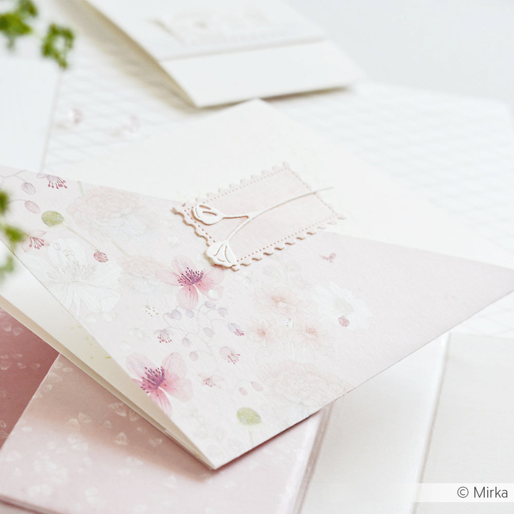 Zartrosa geblümte Grußkarte von Alexandra Renke mit einem verschnörkelten Blanko-Etikett, umgeben von zartfarbigen Designpapieren und akzentuiert mit der Motivstanze Großes Briefmarken Trio.