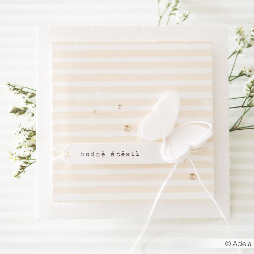 Eine weiße Karte von Alexandra Renke mit einem 3D-Schmetterling und dem tschechischen Text "hodně štěstí" auf einem gestreiften Blumenhintergrund, hergestellt mit Designpapieren und der Motivstanze Büttenrand-Aufleger für eine elegante Note.