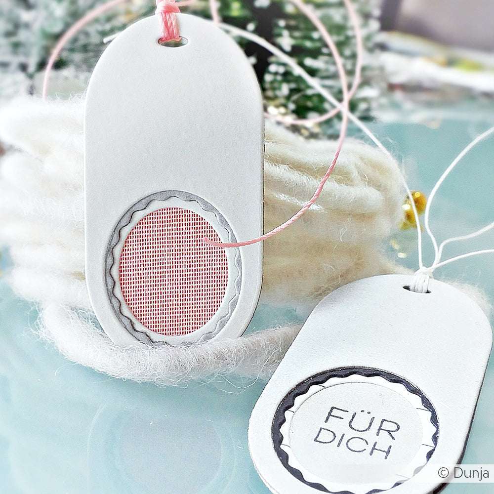 Zwei weiße Alexandra Renke Geschenkanhänger an einer Schnur: einer mit einem rosafarbenen Netzkreis und der andere mit der Aufschrift "FÜR DICH" auf Deutsch.