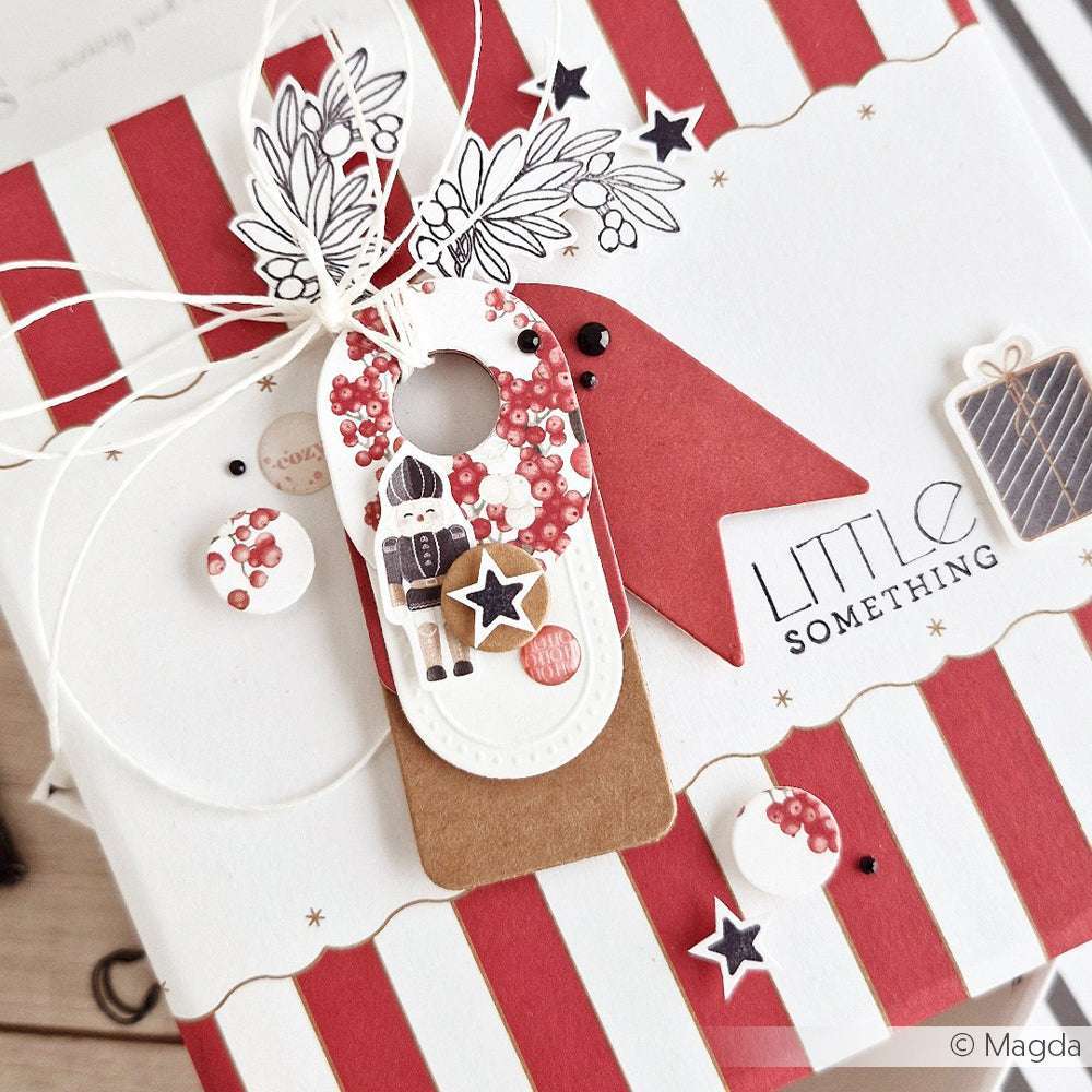 Alexandra Renke Geschenkbox mit roten und weißen Streifen, verziert mit DieCut Systeme Anhängern, Sternen und festlichen Akzenten für einen entzückenden Weihnachtslook.