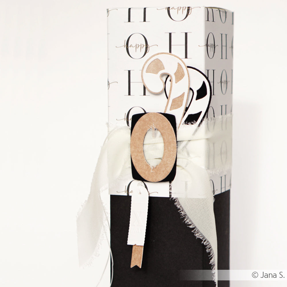 Geschenkverpackung aus schwarzem und weißem Alexandra Renke Designpapier mit Schleife, einer "0" und einer Zuckerstangenverzierung, veredelt mit DieCut Systeme Details für eine einzigartige Note.