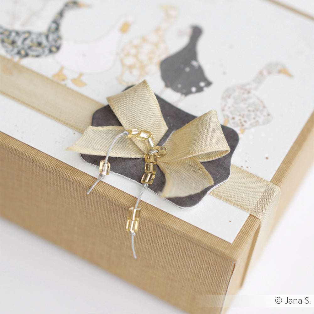 Geschenkbox mit goldenem Band, goldener Schleife und dekorativen Akzenten; Karte mit Enten-Illustrationen - gestaltet mit hochwertigen Designpapieren und DieCut Systemen von Alexandra Renke.