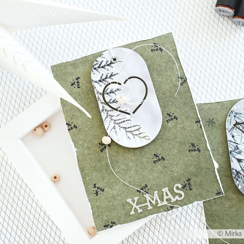 Handgemachte Weihnachtskarte von Alexandra Renke mit XMAS-Text, Grünzeugdruck und einem Herzmotiv, das mit Stanzen und Motivstanze Herz-Schnalle auf weißem und grünem Hintergrund hergestellt wurde.