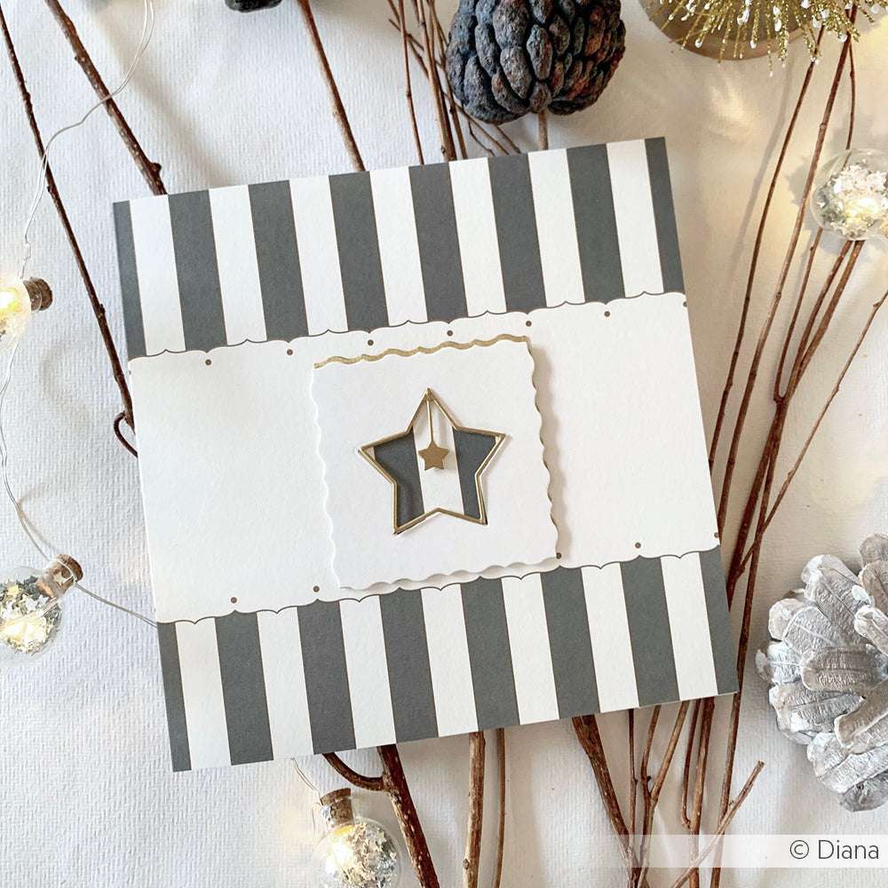 Quadratische Karte mit grauen und weißen Streifen von Alexandra Renke, mit einem goldenen Stern aus der Motivstanze Stern im Stern, umgeben von Tannenzapfen und Lichterketten. Ideal zum Basteln mit Alexandra Renke Designpapieren und Stanzsystemen.