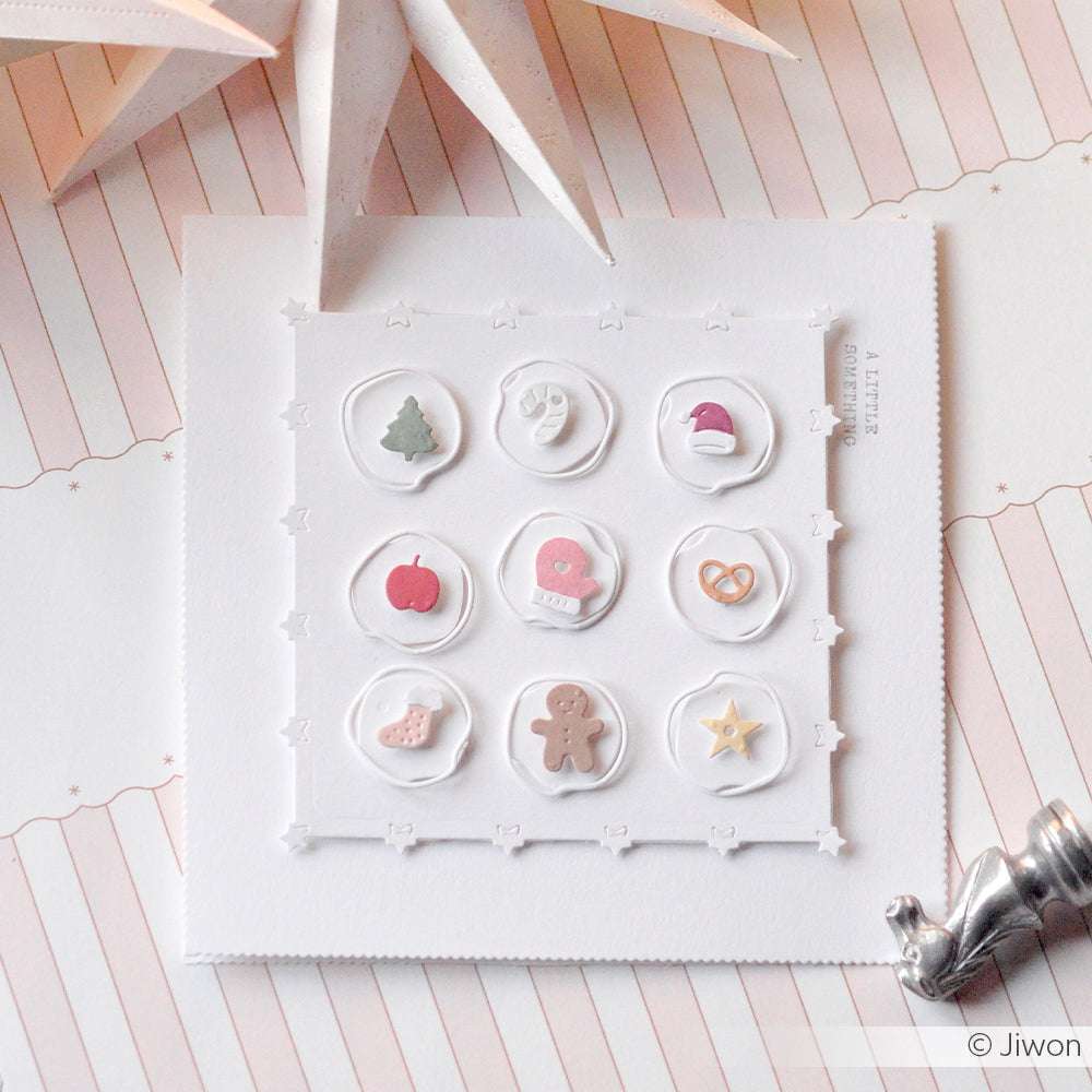 Ein quadratischer weißer Alexandra Renke Kartenaufleger zeigt neun pastellfarbene Weihnachtssymbole - Baum, Fäustling, Mütze, Lebkuchenmann - ideal für festliche Projekte mit Ihren Stanzsystemen.