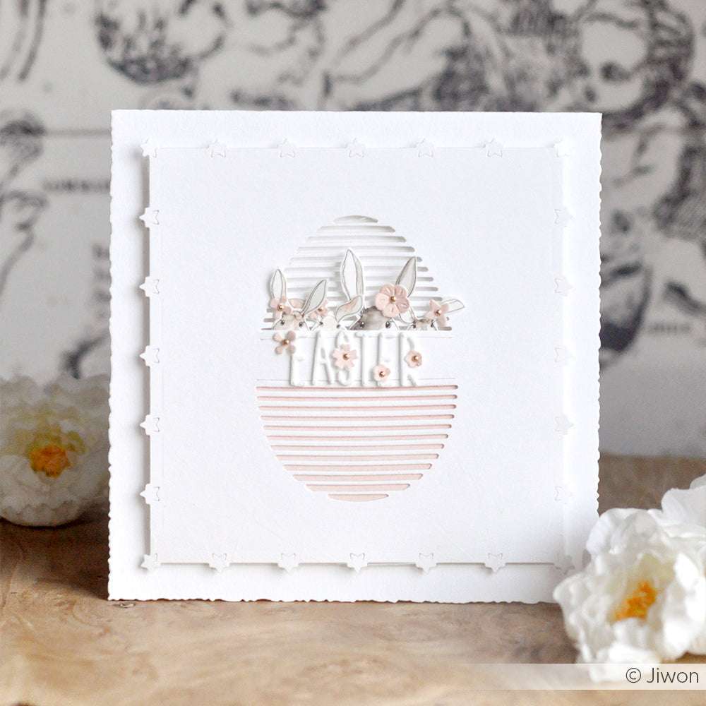 Weiße quadratische Karte mit einem ovalen Ausschnitt aus Alexandra Renke Motivstanze Sternrand Kartenaufleger, verziert mit pastellfarbenen Blumen und Blättern und umgeben von weißen Blüten.