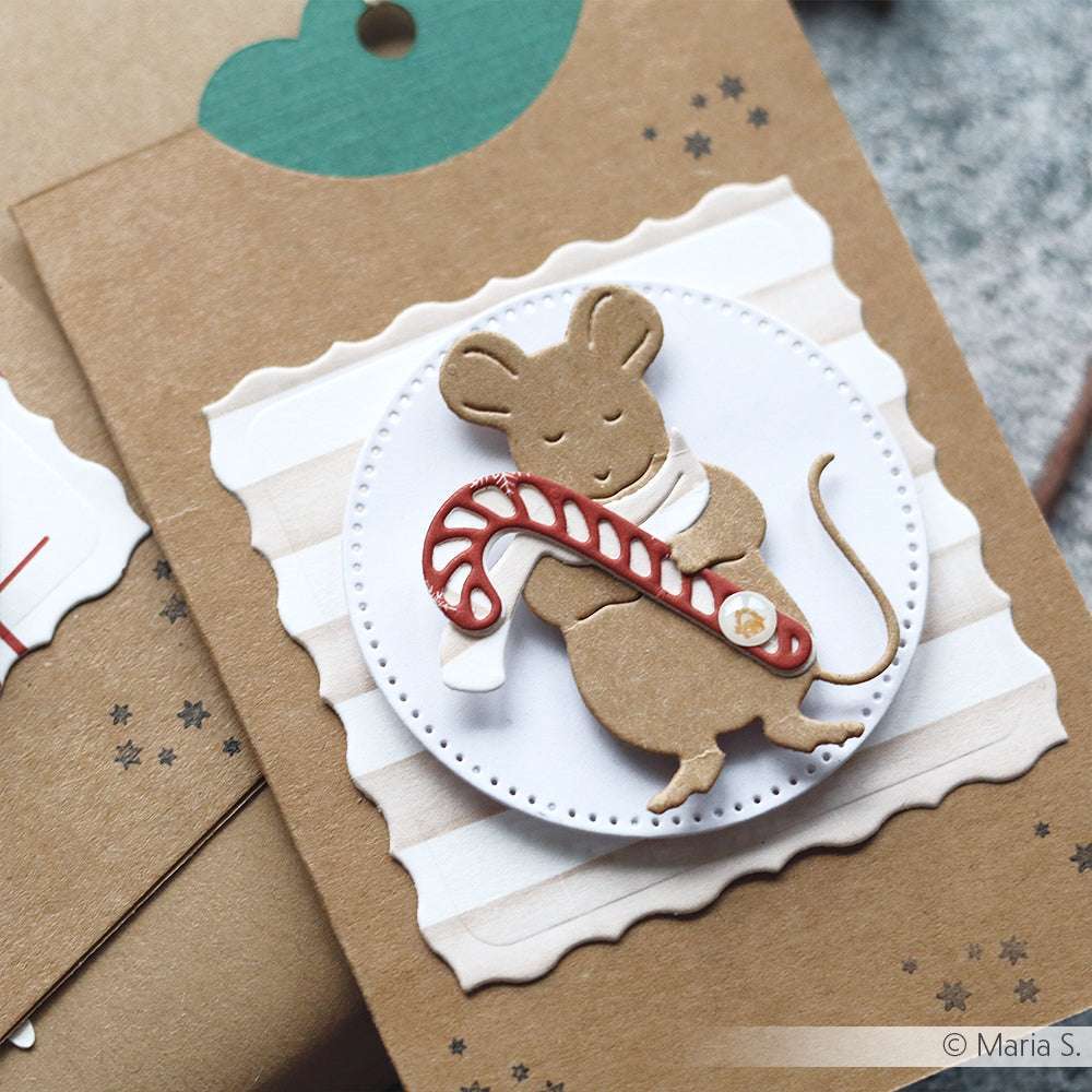 Eine Maus mit Scherenschnitt hält eine Zuckerstange auf einer gestreiften Karte mit Wellenschliff, die mit der Alexandra Renke Kartenaufleger Stanze hergestellt wurde, um zusätzliche Details zu erhalten.