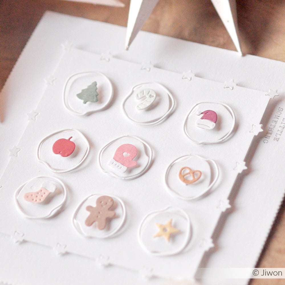 Handgefertigte Karte von Alexandra Renke mit neun Kreisen mit weihnachtlichen Symbolen wie einem Baum, einem Fäustling, einer Mütze und einem Lebkuchenmann, hergestellt mit Designpapieren und der Motivstanze Organische Knöpfe für einzigartige Details.