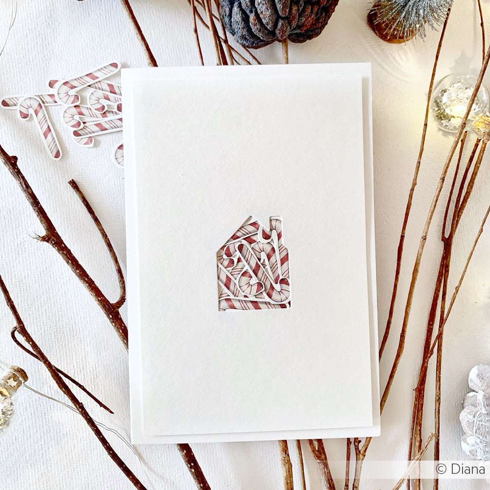 Diese weiße Karte von Alexandra Renke zeigt einen Ausschnitt in Form eines Hauses mit roten und weißen Streifen, akzentuiert mit Zweigen und festlichem Weihnachtsschmuck.