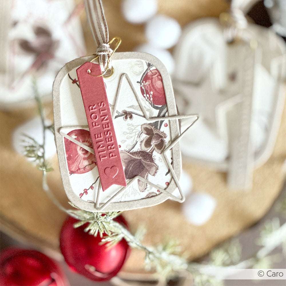 Alexandra Renke Geschenkanhänger mit floralem Design aus Deep Edge Stanzen, verziert mit einem Metallstern und einem roten Etikett "TIME FOR PRESENTS" auf einem festlichen Hintergrund.