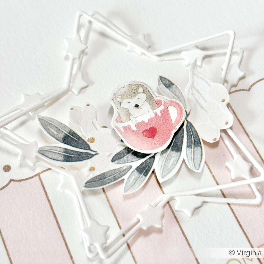 Ein niedlicher Igel in einer rosafarbenen Teetasse sitzt zwischen Blättern in einem weißen Sternenrahmen, gestaltet mit dem Alexandra Renke Motivstanze Sternenzauber Rahmen Set, auf charmanten Alexandra Renke Designpapieren.