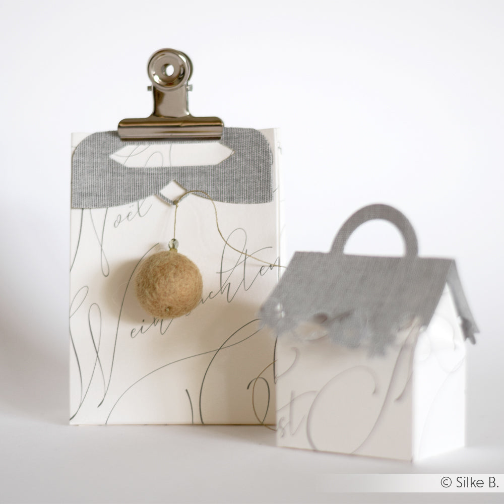 Zwei dekorative weiße Geschenkboxen von Alexandra Renke mit grauen Akzenten, hergestellt mit Stanzsystemen Dies. Die eine hat einen Clip und eine Filzkugel, die andere einen Motivstanze Eleganter Tütengriff für einen eleganten Look.