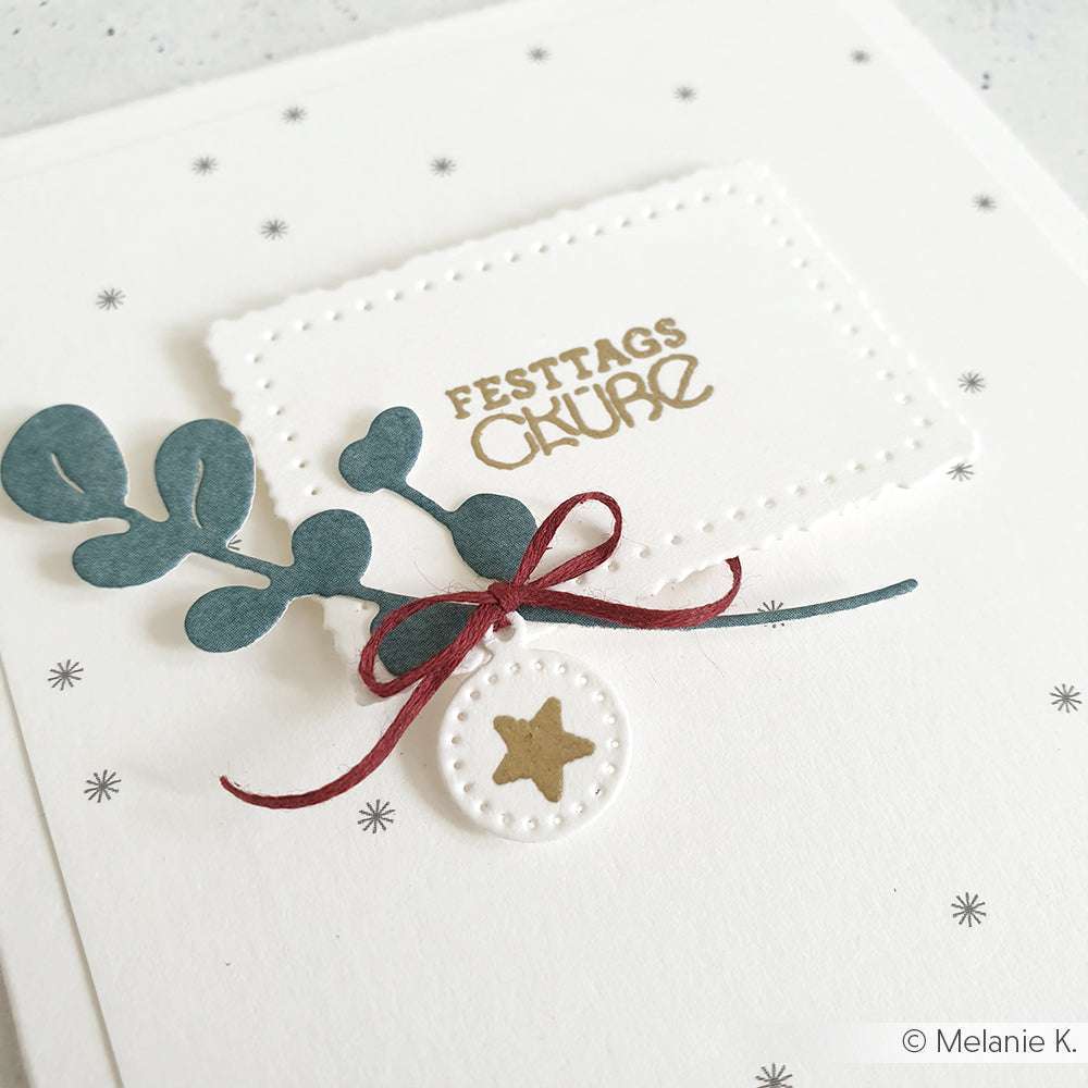 Handgefertigte Weihnachtskarte von Alexandra Renke mit "FESTTAGS GRÜßE" in Gold, Blattwerk, roter Schleife und Stern-Ornament auf weißem 200g Designpapier, veredelt mit Motivstanze Rechteckige Schicht-Etiketten für einen eleganten Touch.