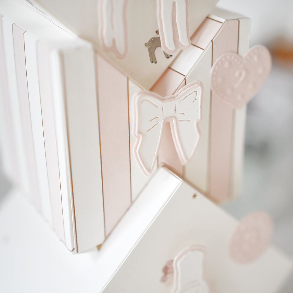 Nahaufnahme von pastellrosa und weiß gestreiften Geschenkschachteln mit Schleifen und Herzverzierungen, hergestellt mit Alexandra Renke DieCut Systemen und veredelt mit der Motivstanze Schicht Schleife für einen charmanten Touch.