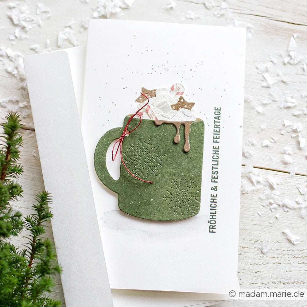 Handgemachte Weihnachtskarte von Alexandra Renke mit einem grünen Becher, Sternen, Schlagsahne und einem deutschen Gruß. Hergestellt mit DieCut Systemen und hochwertigen Designpapieren für charmante Details.