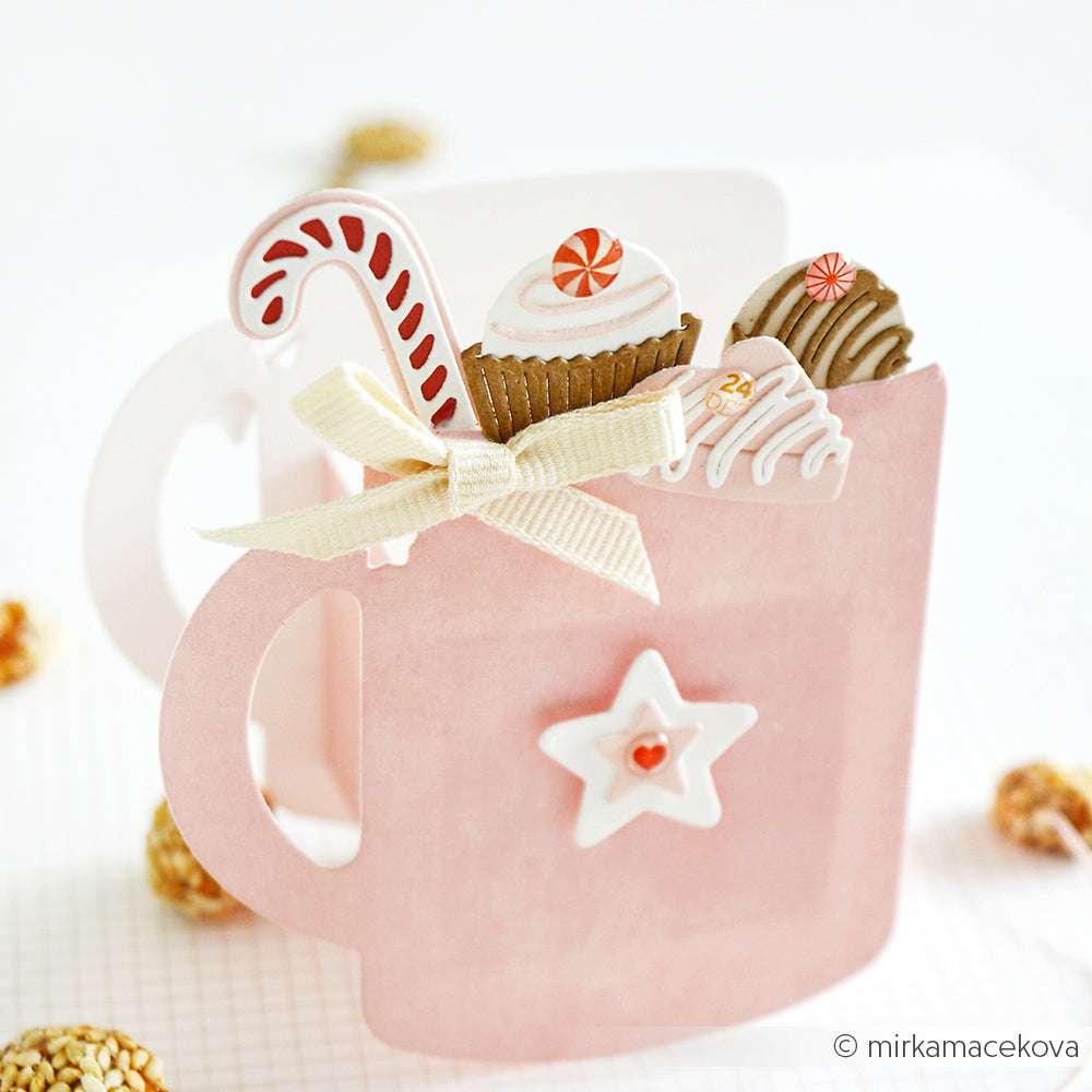 Eine rosafarbene Karte in Form eines Bechers von Alexandra Renke, gestaltet mit Motivstanze Tassen Tags und DieCut Systemen, gefüllt mit Süßigkeiten und Leckereien, verziert mit einer Schleife und einem Stern, dargestellt auf einem hellen Hintergrund.