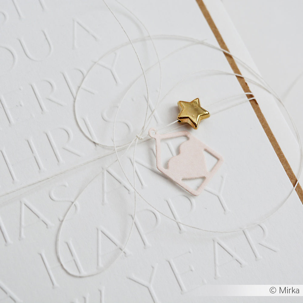 Weiße Karte von Alexandra Renke mit geprägtem Text, weißer Kordel, rosafarbenem Haus Stern Herz Anhänger, der mit Stanzsystemen ausgeschnitten wurde, und einem kleinen goldenen Sternanhänger an der Spitze.