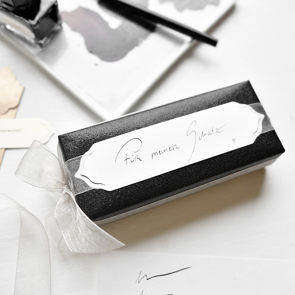 Schwarze Geschenkschachtel mit weißem Band und Etikett mit der Aufschrift "Für meinen Schatz" in handgeschriebener Schrift, hergestellt mit Alexandra Renke Designpapieren und der Stanze Elegantes Etiketten Duo für eine elegante, persönliche Note.