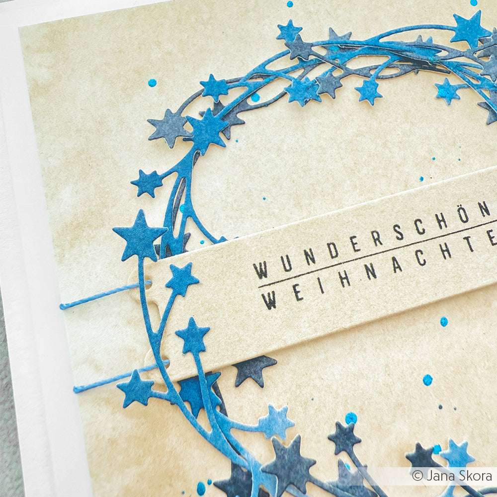 Handgemachte Karte von Alexandra Renke mit einem blauen Sternenkranz und dem Text "Wunderschöne Weihnachten" auf beigem Hintergrund, erstellt mit photopolymeren Klarsichtstempeln.