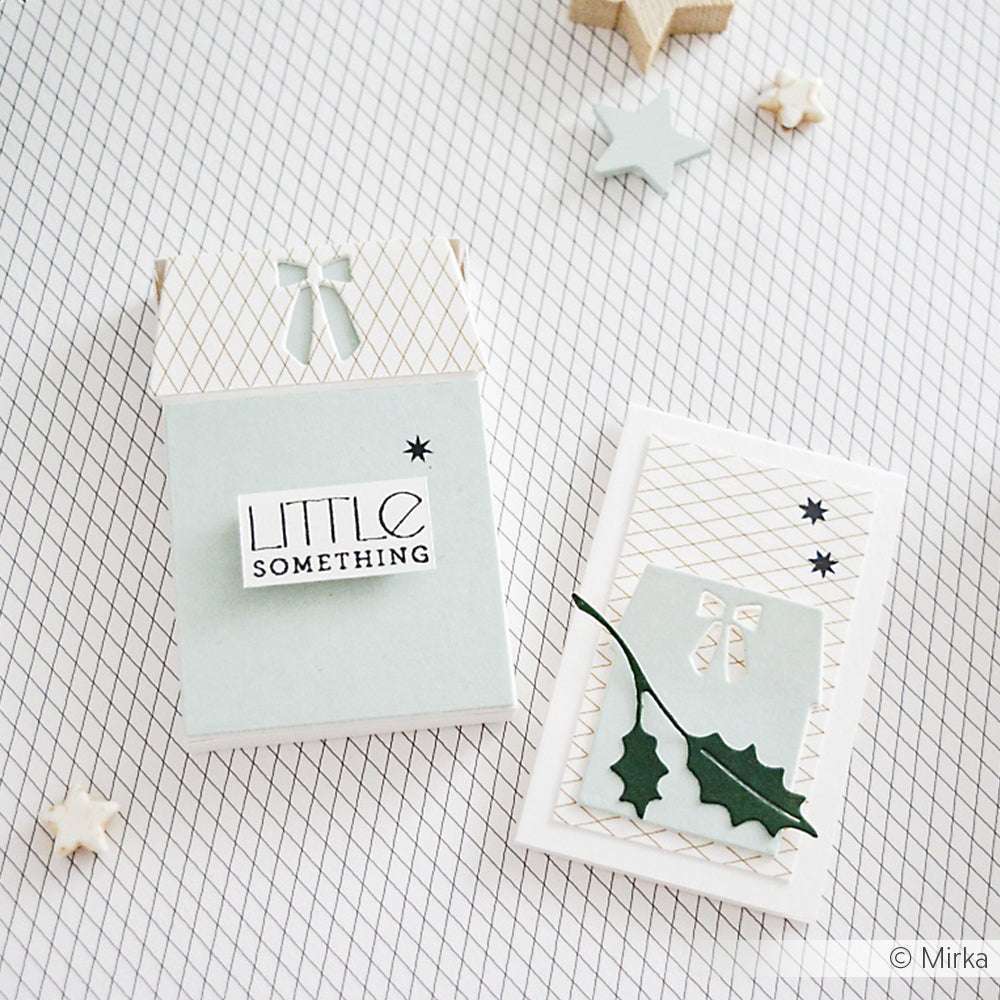 Zwei pastellfarbene Grußkarten mit Schleifen und Stechpalmen auf einem gemusterten Hintergrund, hergestellt mit Alexandra Renke Dies für Designpapier, mit sternförmigen Dekorationen in der Nähe.