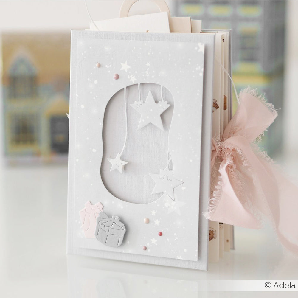 Handgefertigte weiße Grußkarte von Alexandra Renke mit Stern, Geschenk und Schleife von DieCut Systeme, die an der Seite mit einem rosafarbenen Band verziert ist.