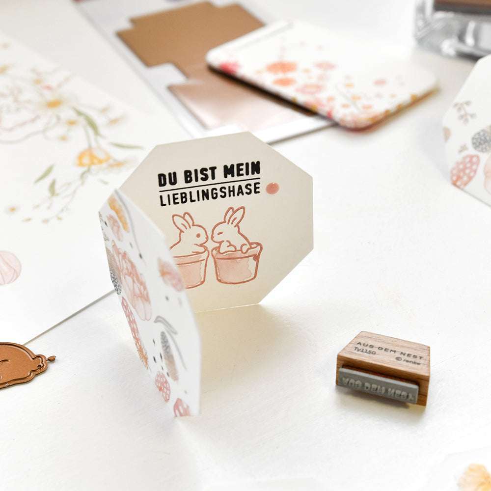 Achteckige Alexandra Renke PAPPcut®ies Karte mit zwei Hasen und dem Text "Du bist mein Lieblingshase", abgebildet auf einem weißen Schreibtisch mit Schreibwaren - ideal für kreative Projekte mit Deep Edge Motivstanzen.