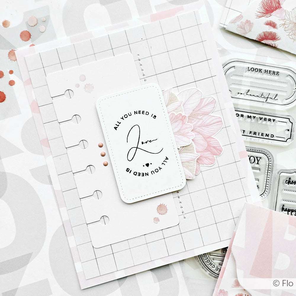 Eine handgefertigte Karte mit floralem Design, gitterförmigem Hintergrund und "All you need is love" in der Mitte - hergestellt mit Alexandra Renke-Produkten für gestochen scharfe Details.