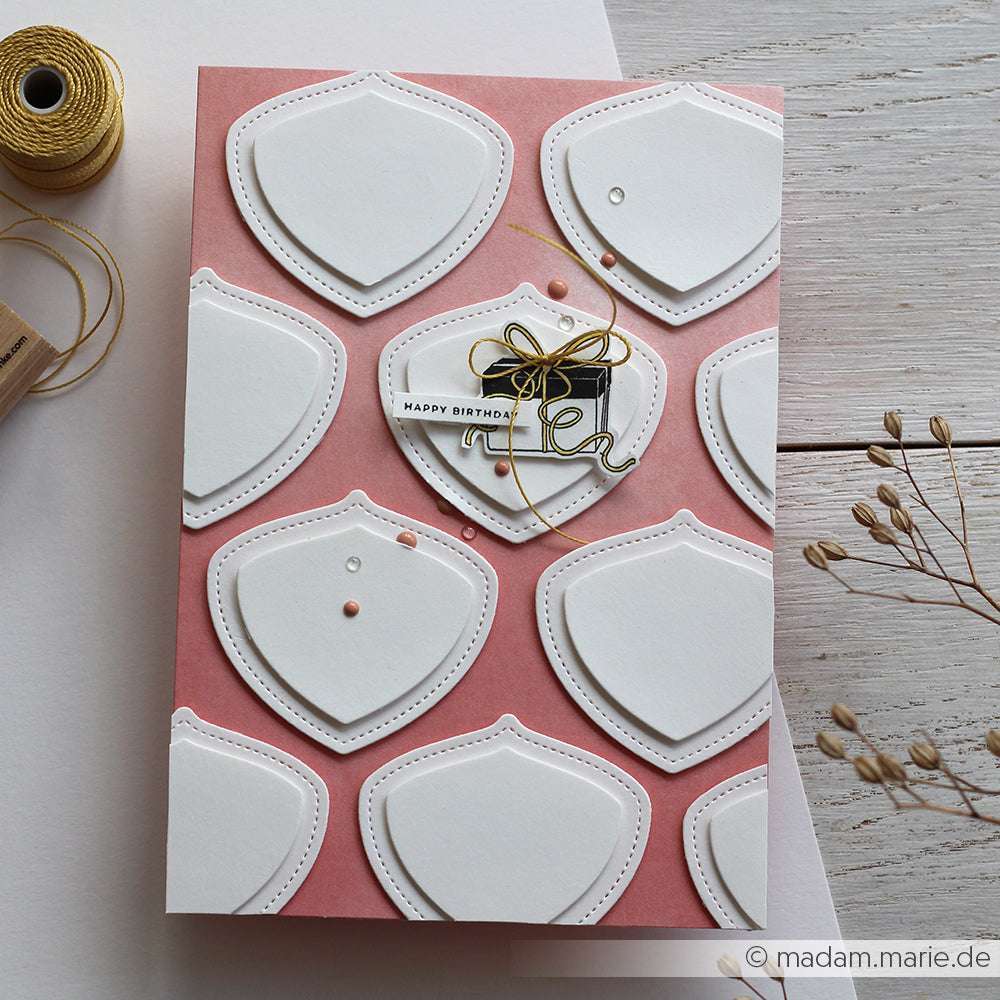 Rosa Geburtstagskarte mit geschichteten weißen Schildformen, hergestellt mit der Alexandra Renke Motivstanze Schildform Duo, verziert mit einer goldenen Fadenschleife und kleinen Verzierungen.