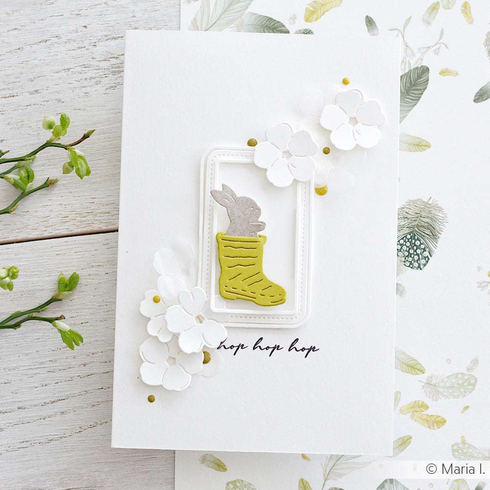 Handgefertigte Karte mit einem Hasen in einem grünen Strumpf, weißen Blumen und dem Text "hop hop hop" auf weißem Untergrund - hergestellt mit Alexandra Renke Deep Edge Motivstanzen für zusätzlichen Charme.