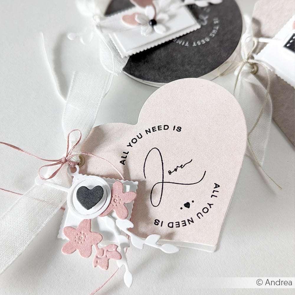 Herzförmige Karte von Alexandra Renke, gestaltet mit PAPPcut®ies. Mit dem Text "All you need is love", rosa Blumen, einer Schleife und einem kleinen Herzanhänger.