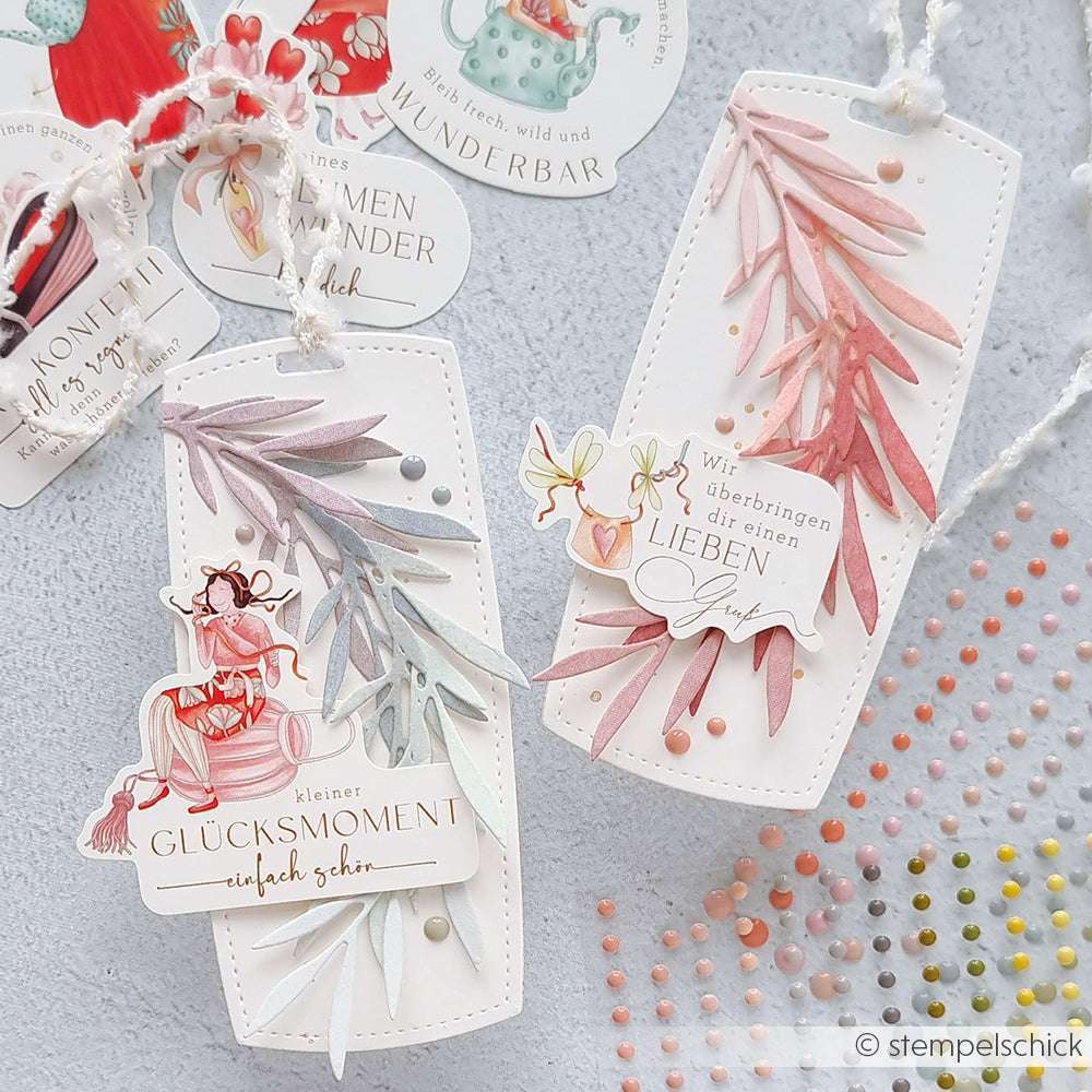 Zwei dekorative Geschenkanhänger von Alexandra Renke, hergestellt mit Deep Edge Motivstanzen und PAPPcuties, zeigen pastellfarbene Blätter, kleine Perlen und deutschen Text auf hellem Hintergrund.