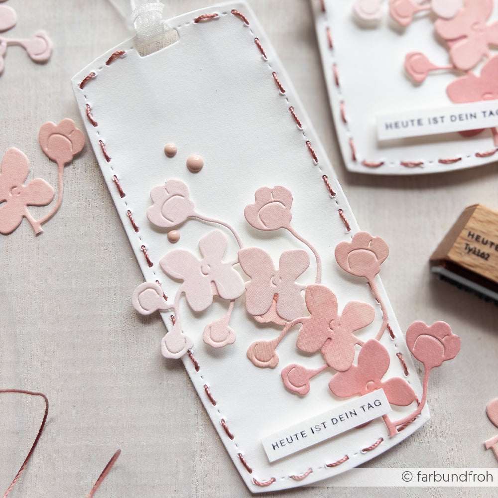 Ein handgefertigtes Lesezeichen von Alexandra Renke mit rosa Papierblumen aus Deep Edge Motivstanzen und dem Text "HEUTE IST DEIN TAG" auf weißem Hintergrund.