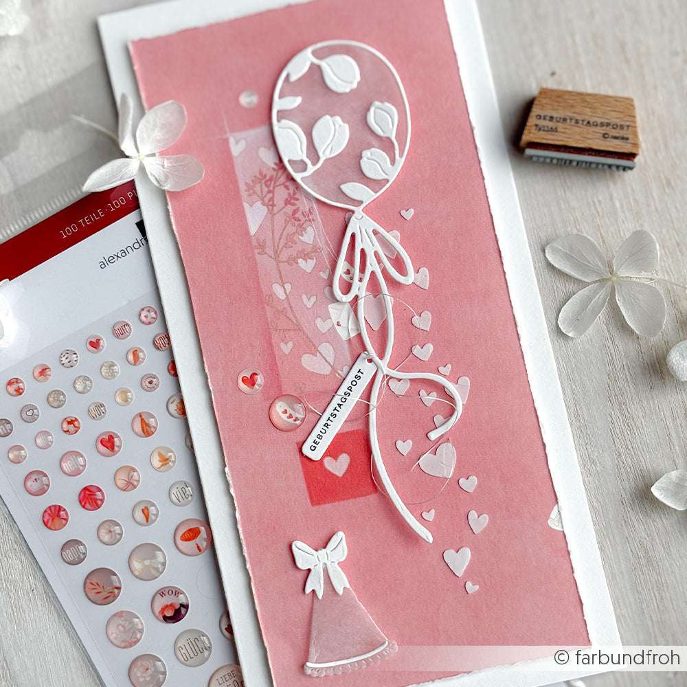 Handgefertigte rosafarbene Karte mit weißem Luftballon, Herzen und einer kleinen Mütze mit Schleife, akzentuiert mit Stickern und einem Stempel - hergestellt mit Alexandra Renke Deep Edge Motivstanzen und PAPPcut®ies für präzise Details.