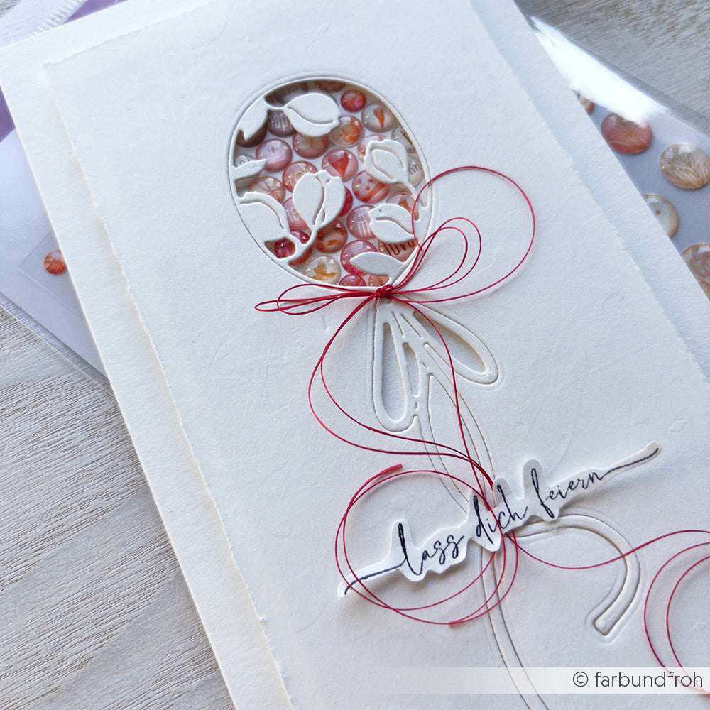 Handgemachte Karte von Alexandra Renke mit einem ballonförmigen Ausschnitt, Perlen, roter Schleife und dem Text "Lass dich feiern", hergestellt mit PAPPcut®ies.