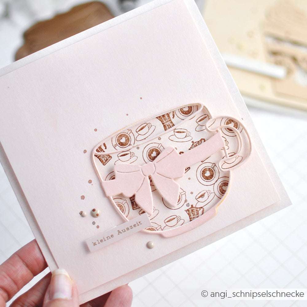 Eine handgefertigte Karte von Alexandra Renke mit einer Teetasse mit Schleife und Kaffeemotiv, hergestellt mit PAPPcut®ies und der Motivstanze Große Schleifentasse, in der Hand gehalten.