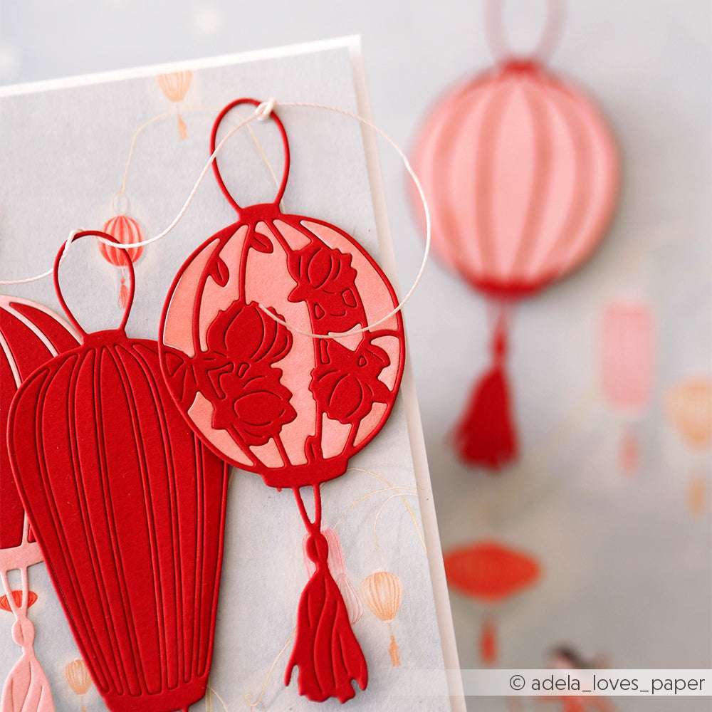 Rote und rosafarbene Papierlaternen mit Quasten auf einer Karte, hergestellt mit Alexandra Renke Deep Edge Motivstanzen oder der Stanze Großer runder Lampion, wobei die Laternen im Hintergrund verschwommen zu sehen sind.