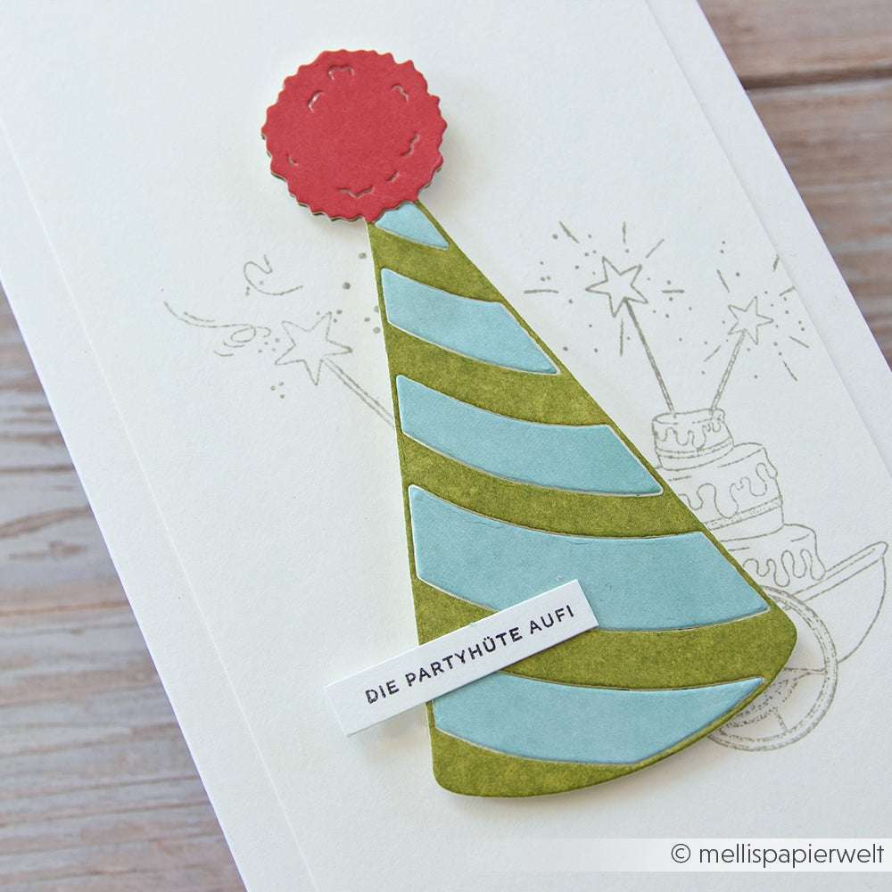 Eine handgefertigte Karte von Alexandra Renke mit einem gestreiften Partyhut (Motivstanze Großer Partyhut), roter Bommel und dem Text "DIE PARTYHÜTE AUFI" auf weißem Hintergrund.