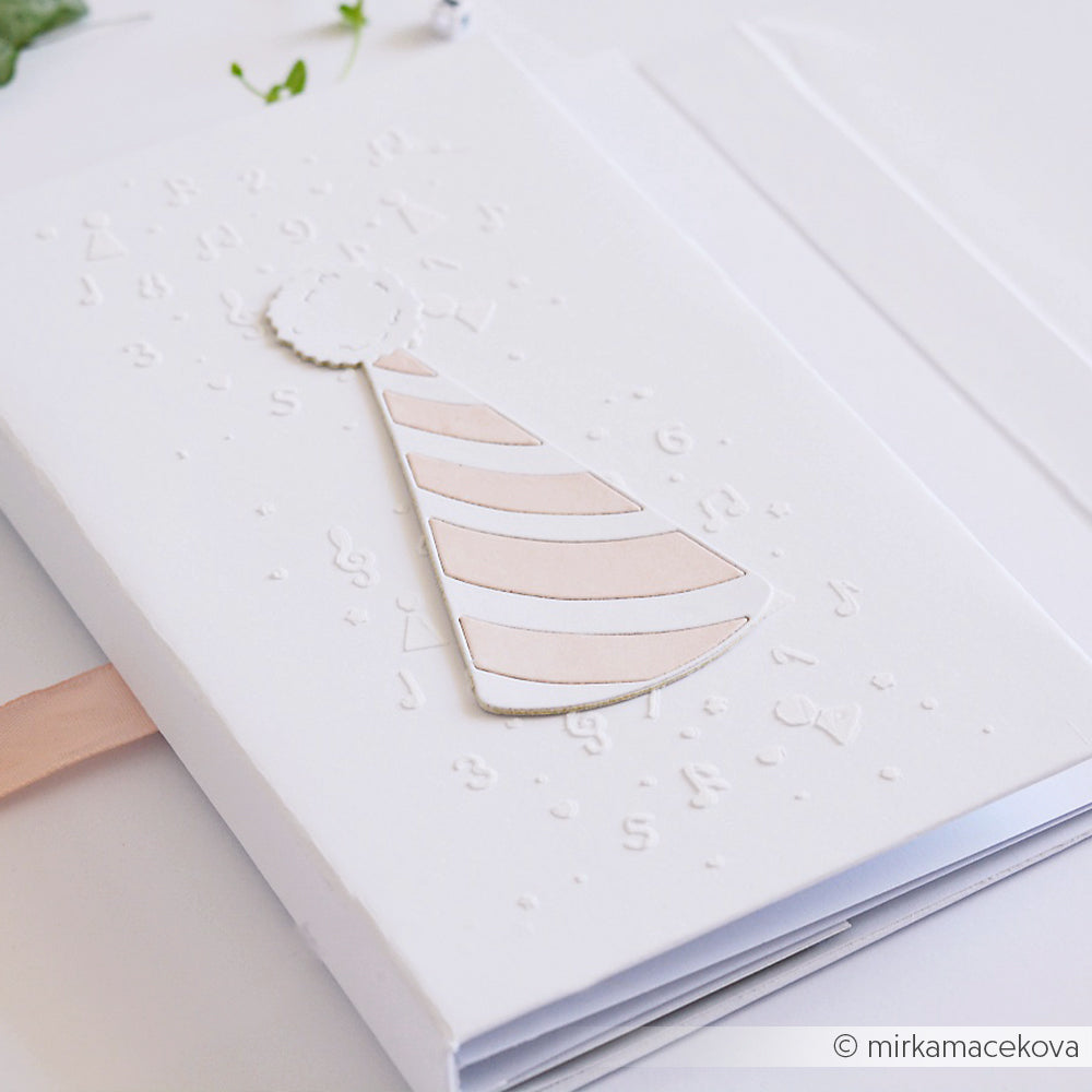 Eine weiße Karte von Alexandra Renke zeigt ein zartrosa und weißes Partyhut-Motiv auf dem Umschlag, das mit Deep Edge Motivstanzen für gestochen scharfe Details hergestellt wurde.